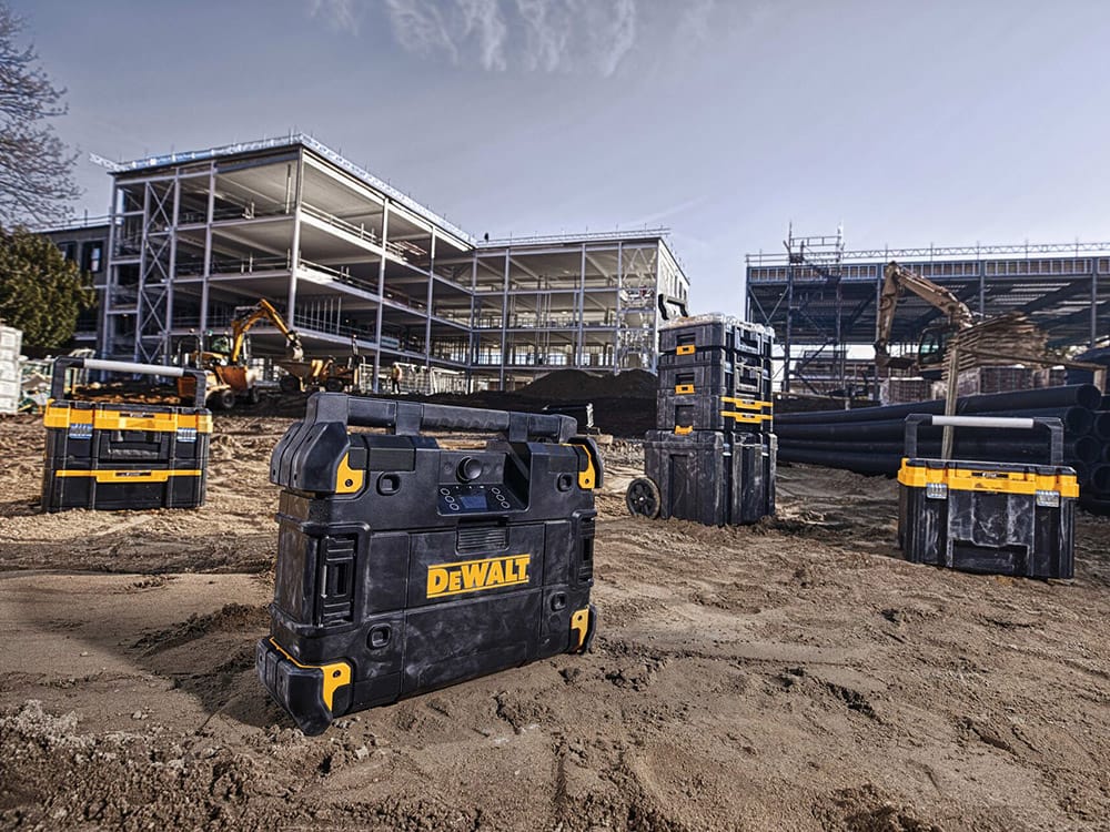 T stak portable Bluetooth radio and charger placed next to other tool cases at a worksite.